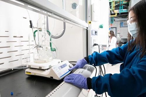 A researcher working with lab equipment. A Bio-Based Solution—An NREL researcher synthesizes a plant-derived epoxy that can be fully depolymerized at room temperature with a special catalyst. Photo by Dennis Schroeder, NREL