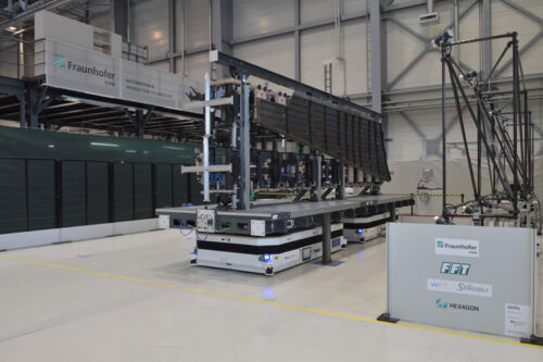The first station of the "UniFix" flow line: The newly developed mobile holding fixture, which is navigating by virtually coupled AGV systems, transports the precisely positioned CFRP vertical tail plane element into the camera arena, where the shape retention of the holding fixture is checked. © Fraunhofer IFAM